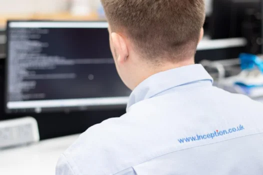 un bărbat care folosește computerul în timp ce vorbește la telefon prin căști